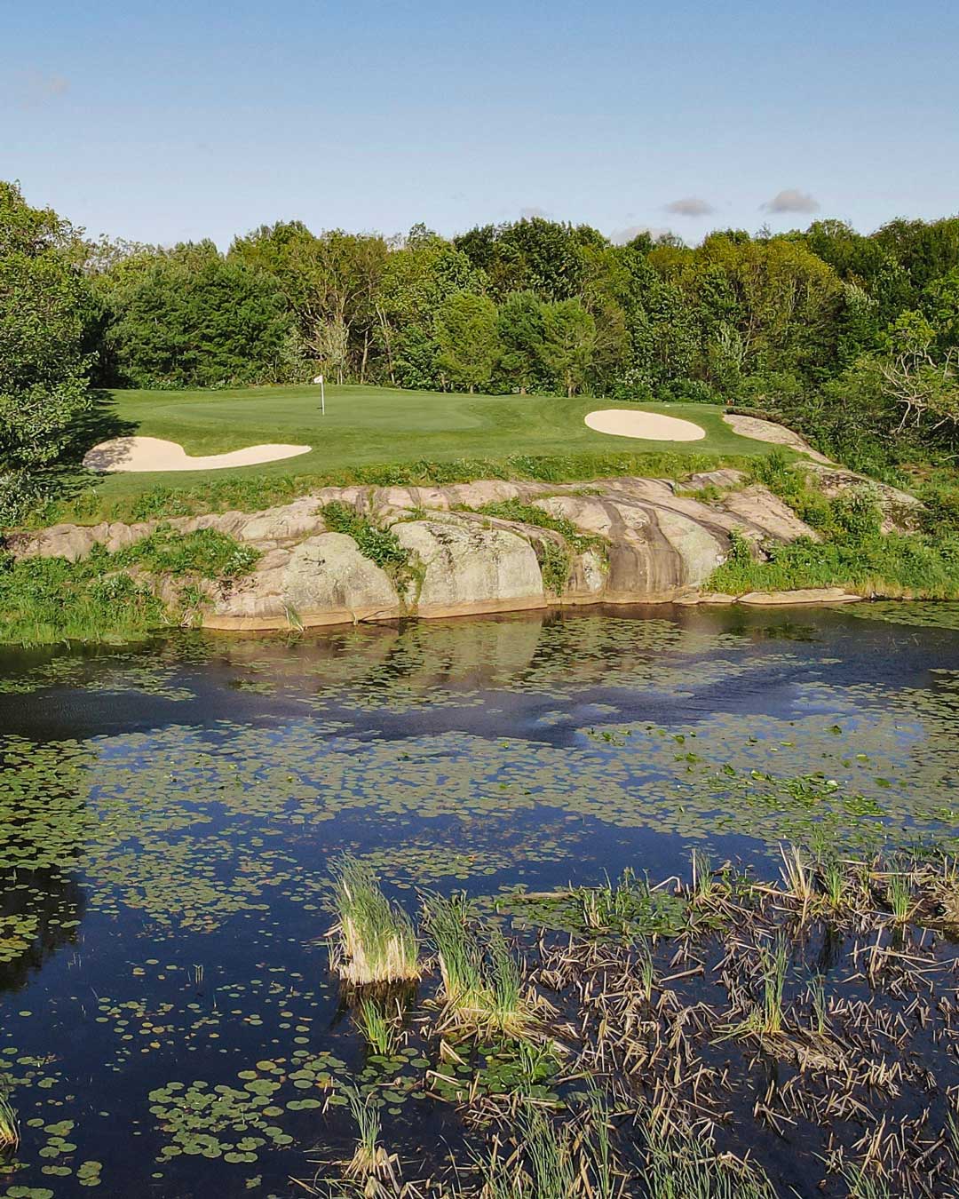 Muskoka golf green with water and rock face